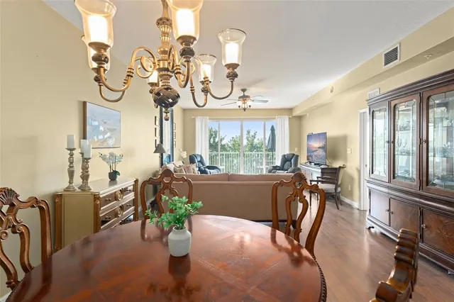 a view of a dining room with furniture a chandelier windows and wooden floor