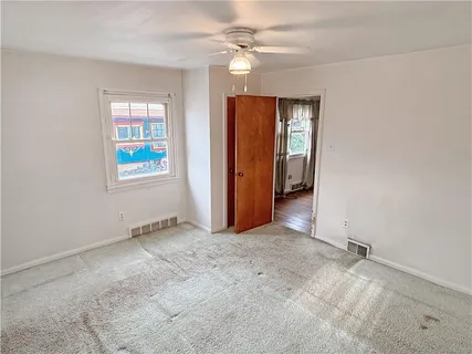 an empty room with windows and ceiling fan