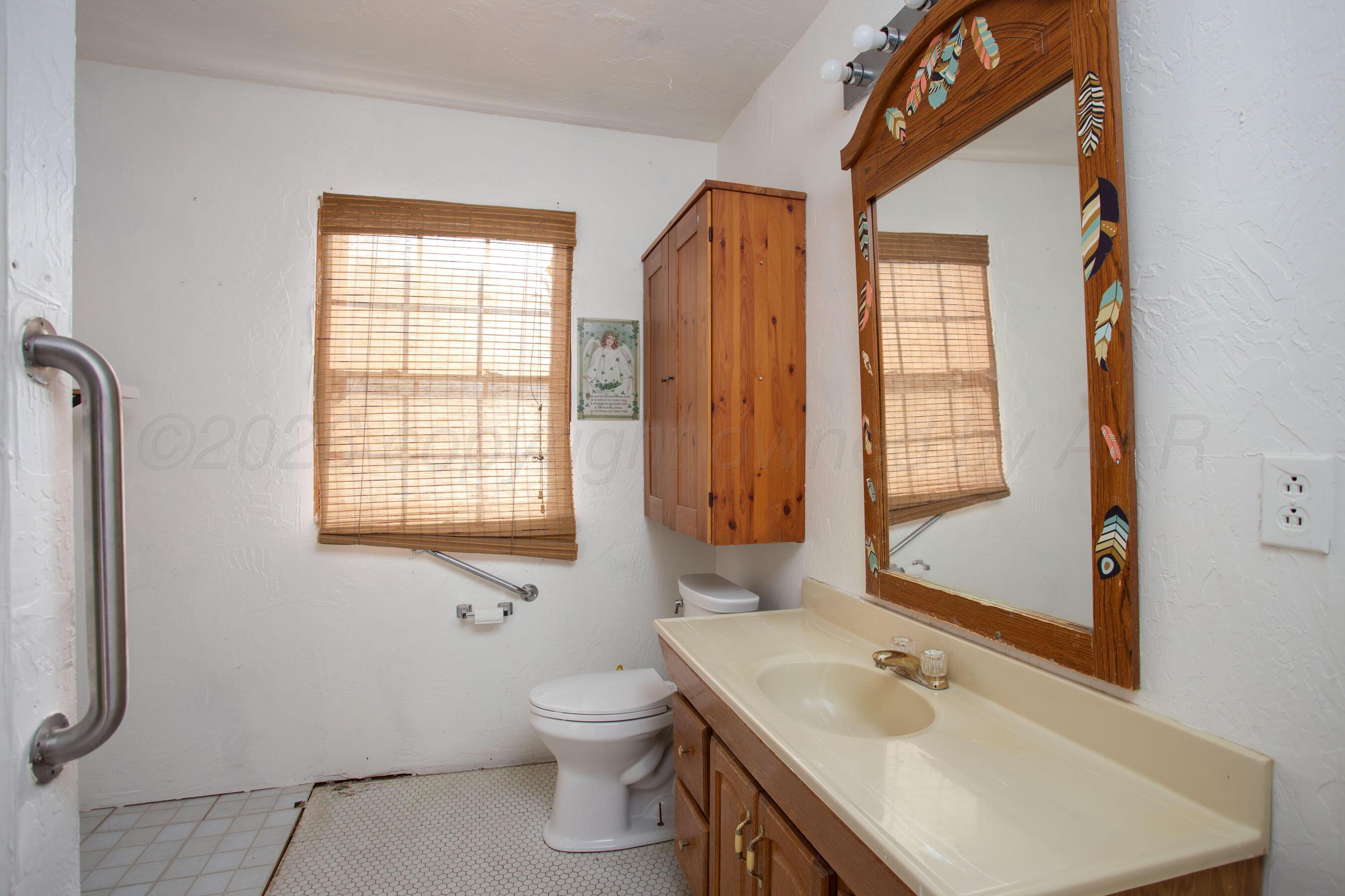 4223 Southwest 11th Avenue Amarillo, TX 79106 - Photo 22 of 26 a bathroom with a sink mirror and a bathtub