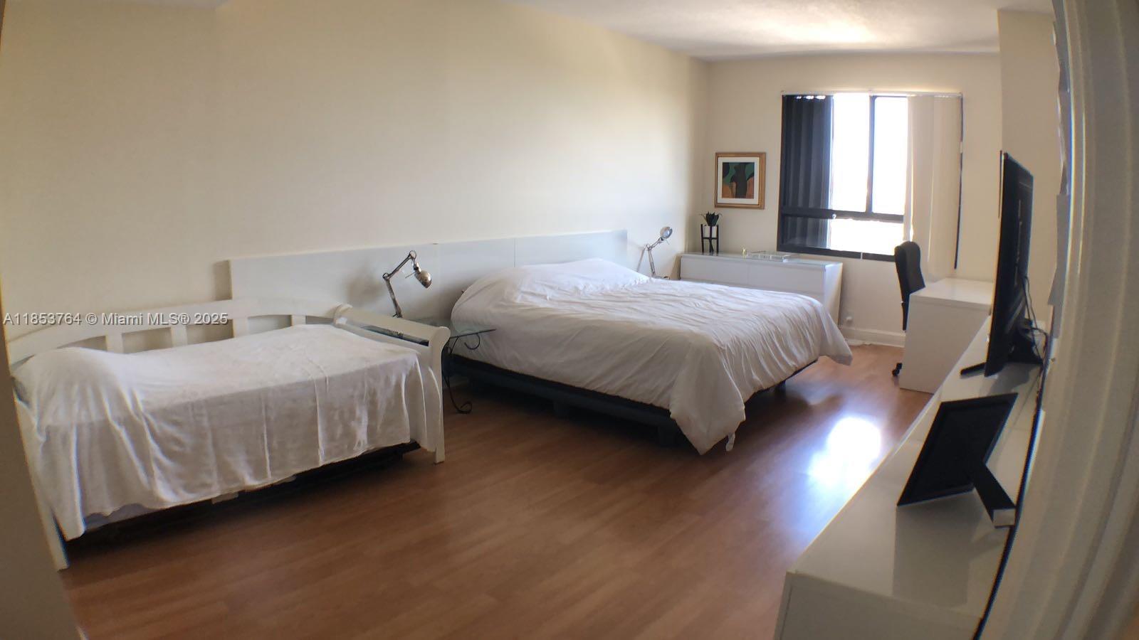 151 Crandon Boulevard, Unit 833 Key Biscayne, FL 33149 - Photo 8 of 12 a bedroom with a bed lamps and wooden floor