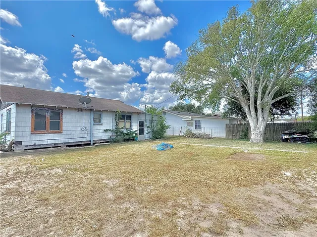 a view of a house with a yard and a large tree
