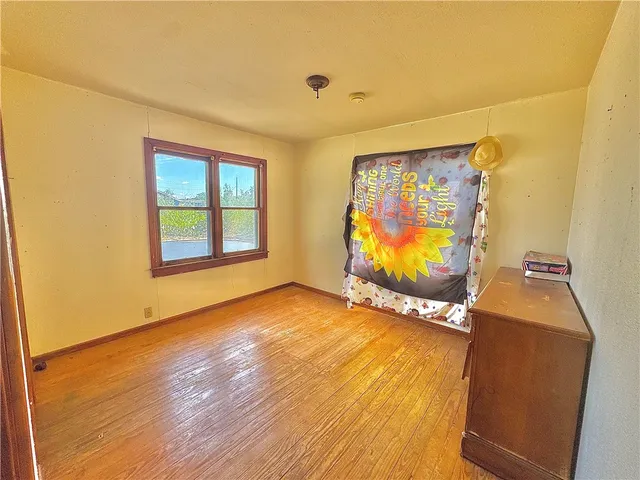 a view of an empty room with window and wooden floor