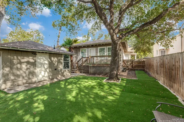 a view of a backyard with table and chairs and a large tree