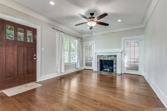 a view of an empty room with wooden floor fireplace and a window