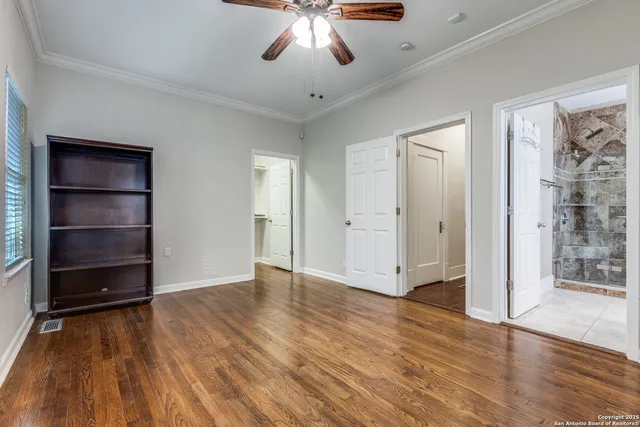 an empty room with wooden floor closet and windows