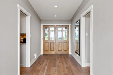 a view of a hallway with wooden floor and windows
