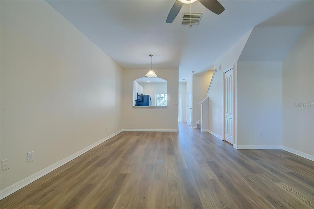 15706 Stable Run Drive Spring Hill, FL 34610 - Photo 11 of 40 an empty room with wooden floor chandelier fan and windows