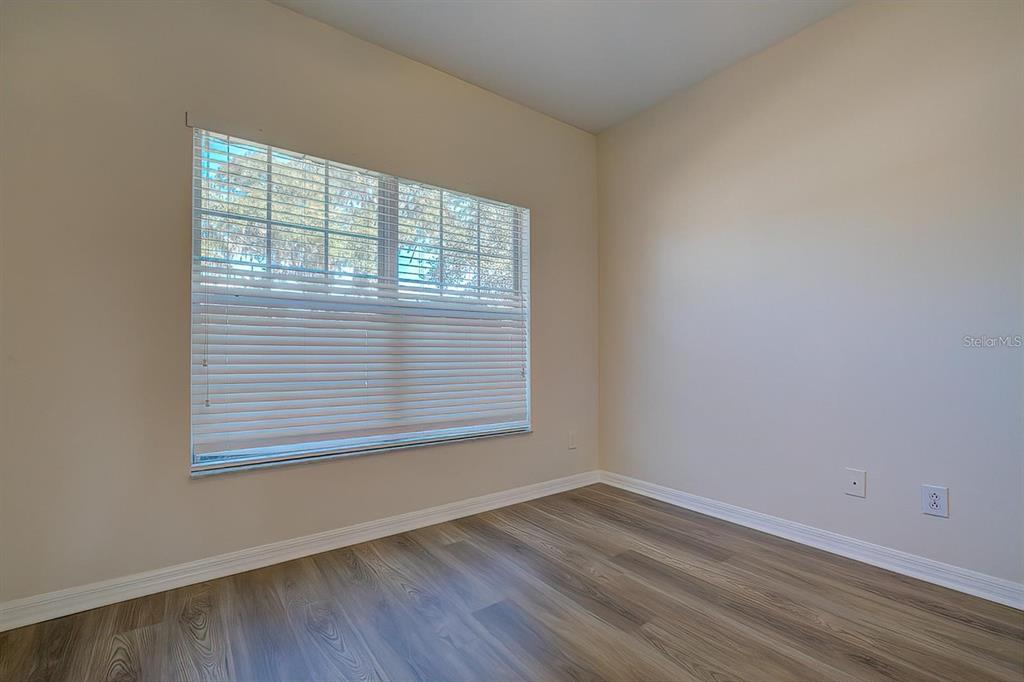 15706 Stable Run Drive Spring Hill, FL 34610 - Photo 12 of 40 an empty room with wooden floor and windows