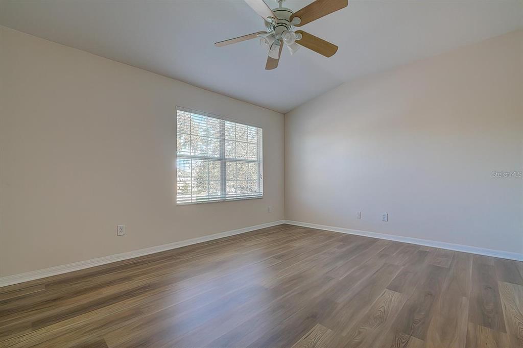 15706 Stable Run Drive Spring Hill, FL 34610 - Photo 30 of 40 an empty room with wooden floor fan and windows