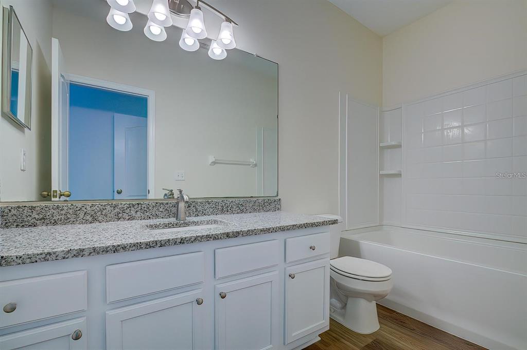 15706 Stable Run Drive Spring Hill, FL 34610 - Photo 34 of 40 a bathroom with a granite countertop sink a toilet and bathtub