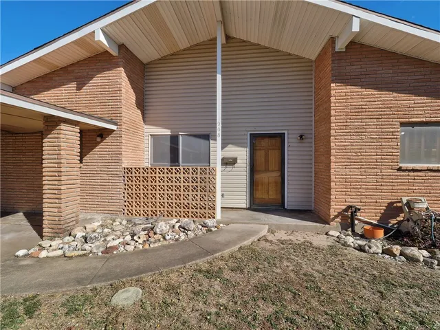 a view of a house with a small yard and parking space