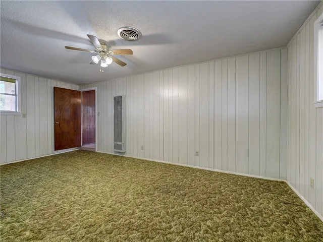 a view of an empty room and chandelier fan