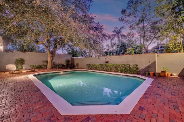 a view of a swimming pool with outdoor seating and trees in the background