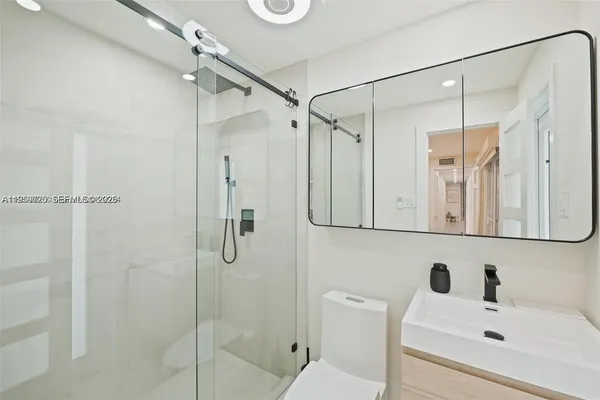 a bathroom with a sink a toilet and shower