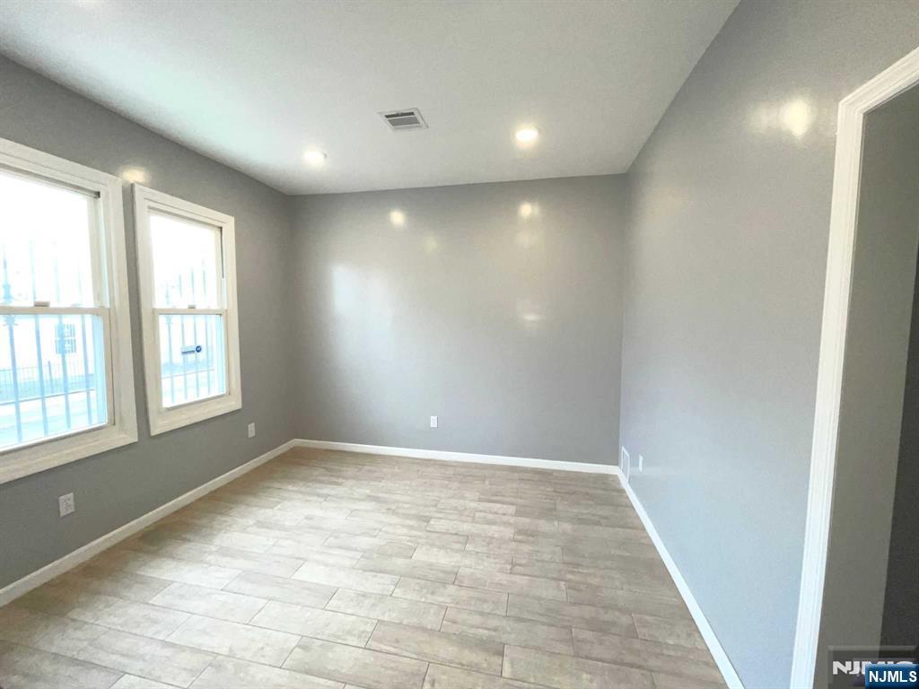 25 Kipp Street Newark, NJ 07108 - Photo 2 of 19 an empty room with wooden floor and windows