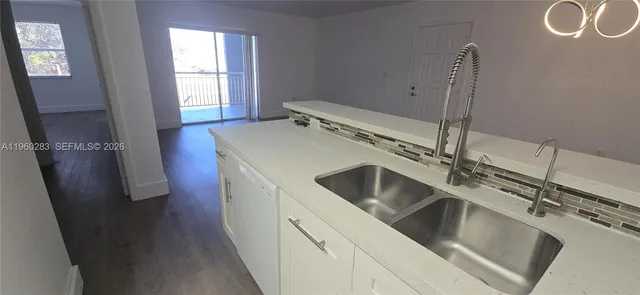 a kitchen with stainless steel appliances a sink a stove a refrigerator with white cabinets and wooden floor