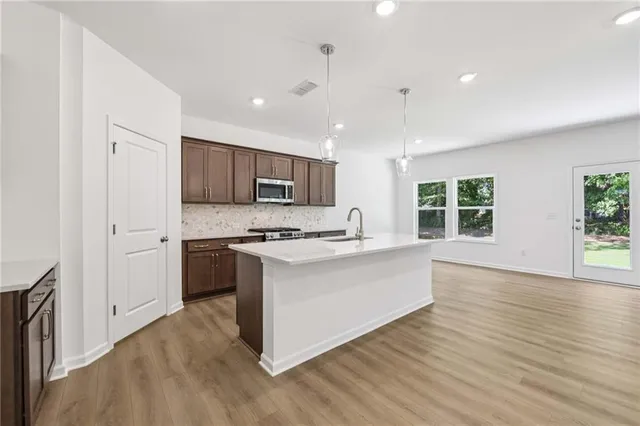 a kitchen with stainless steel appliances granite countertop a stove top oven a sink dishwasher a refrigerator and a oven with wooden floors