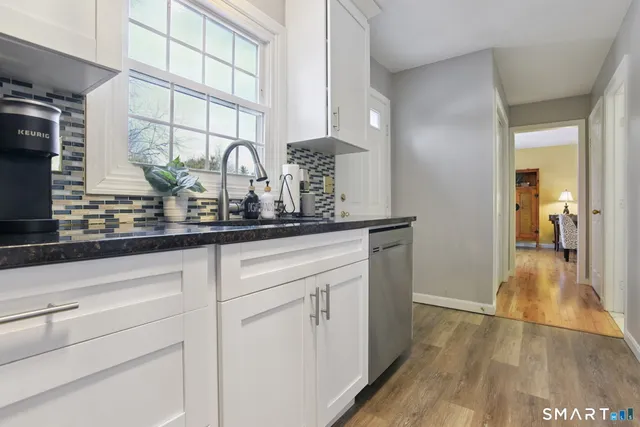 a kitchen with white cabinets and a wooden floor