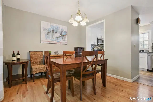 a dining room with wooden floor a chandelier a wooden table and chairs