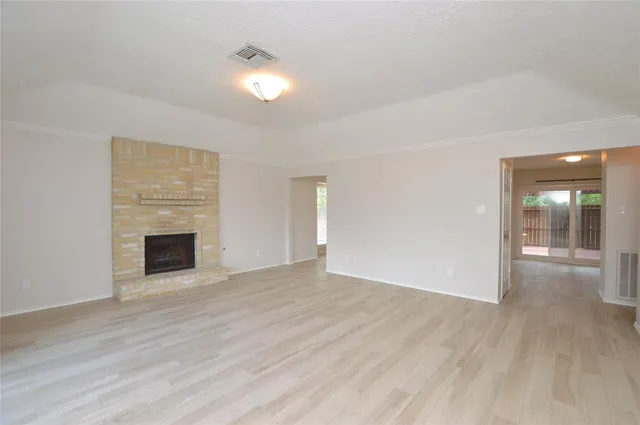 an empty room with wooden floor fireplace and windows