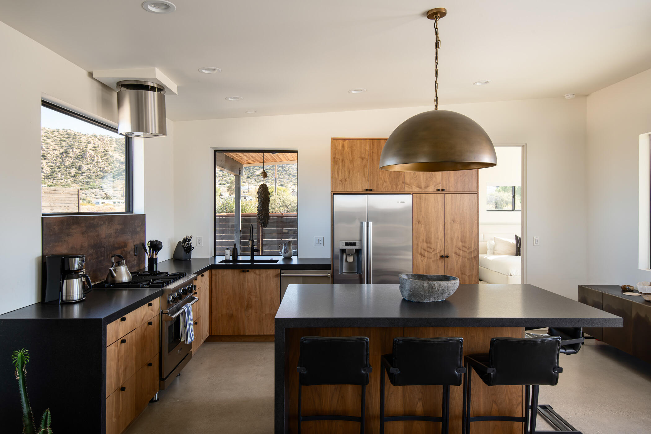 5494 Bronco Road Pioneertown, CA 92268 - Photo 16 of 38 a kitchen with stainless steel appliances a dining table chairs and a window