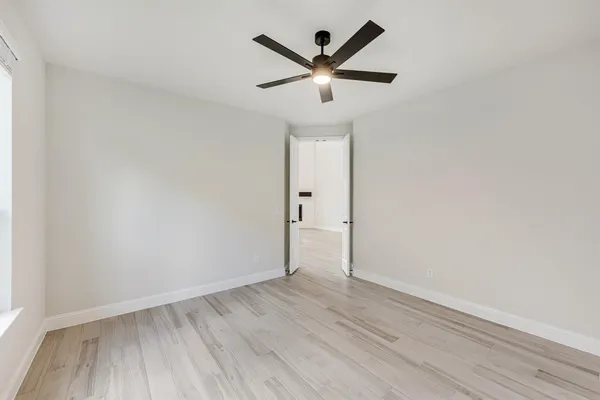 an empty room with wooden floor and ceiling fan