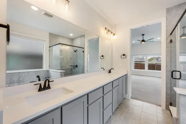 a bathroom with a sink double vanity granite tub shower and a mirror