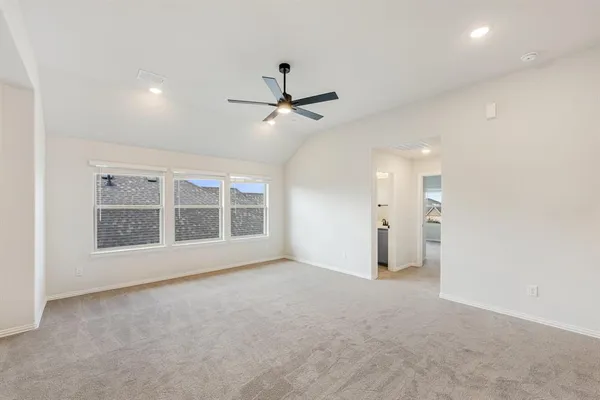 an empty room with chandelier fan and windows