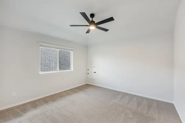 an empty room with ceiling fan and window