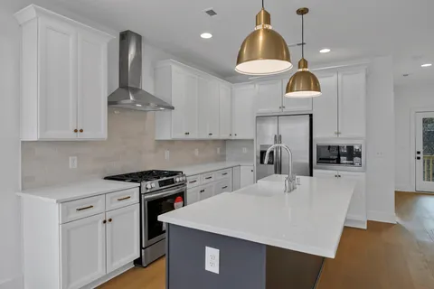 a kitchen with kitchen island granite countertop a sink a stove and refrigerator