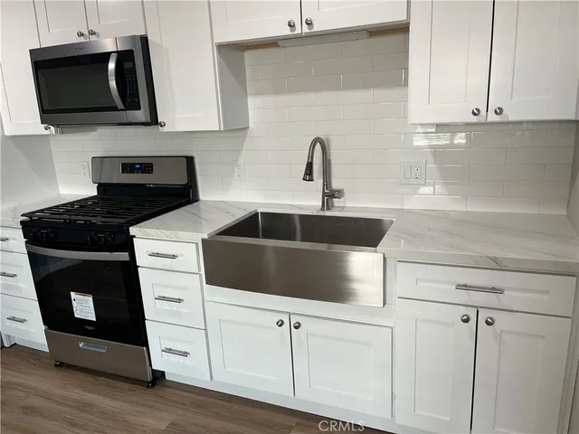 a kitchen with white cabinets and black appliances