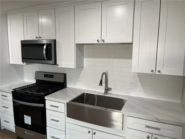 a kitchen with white cabinets a sink and a stove