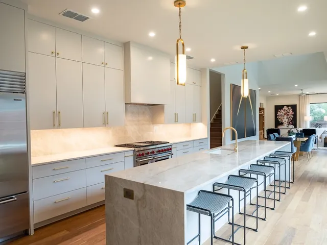 a kitchen with stainless steel appliances granite countertop a stove a sink a refrigerator and white cabinets with wooden floor