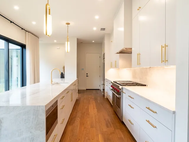 a large kitchen with stainless steel appliances granite countertop a lot of counter space and wooden floors