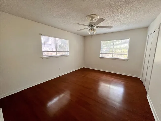 a view of empty room with wooden floor and ceiling fan