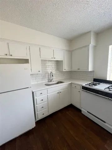 a kitchen with granite countertop white cabinets and white appliances