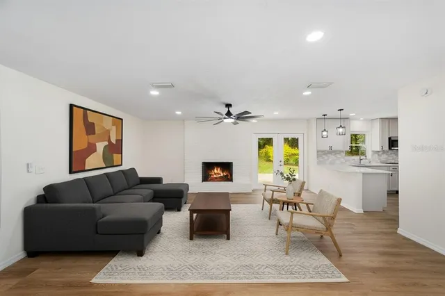 a view of an empty room with wooden floor and a kitchen