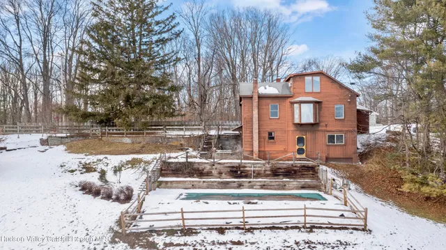 a front view of a house with a yard covered with snow and trees