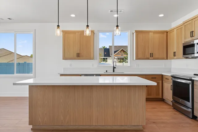 a large kitchen with stainless steel appliances granite countertop a sink a stove and a refrigerator