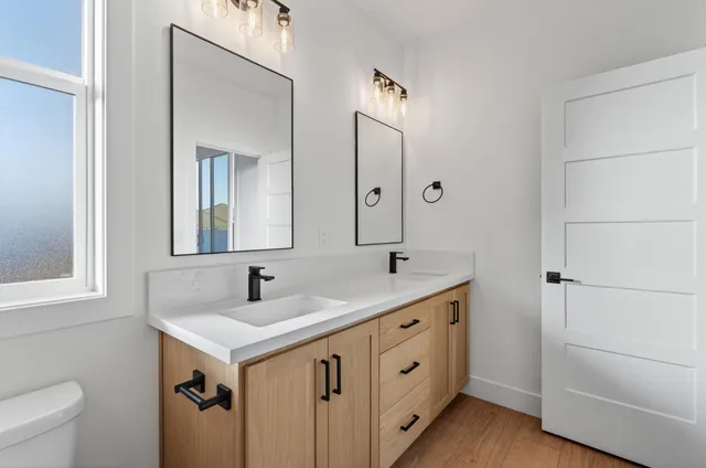 an empty room with wooden floor ceiling fan and windows