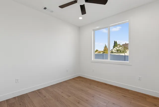 an empty room with wooden floor cabinet and windows