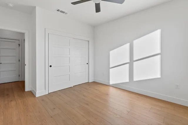 an empty room with wooden floor and windows
