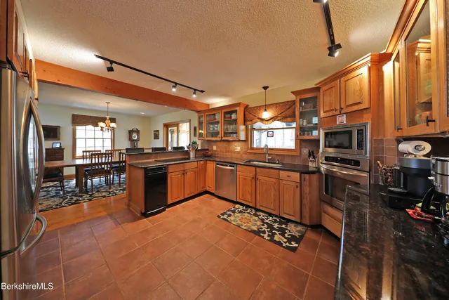 a kitchen with stainless steel appliances kitchen island granite countertop a stove refrigerator and cabinets