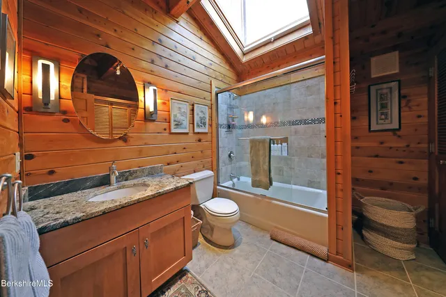 a bathroom with a granite countertop toilet sink and mirror