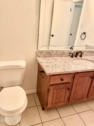a bathroom with a granite countertop toilet sink and mirror