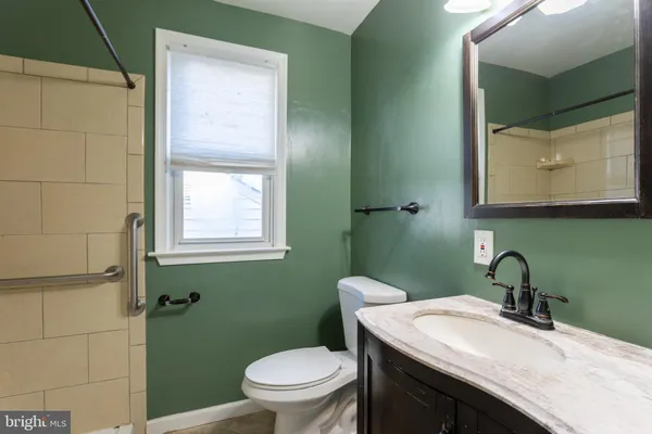 a bathroom with a granite countertop toilet sink and mirror