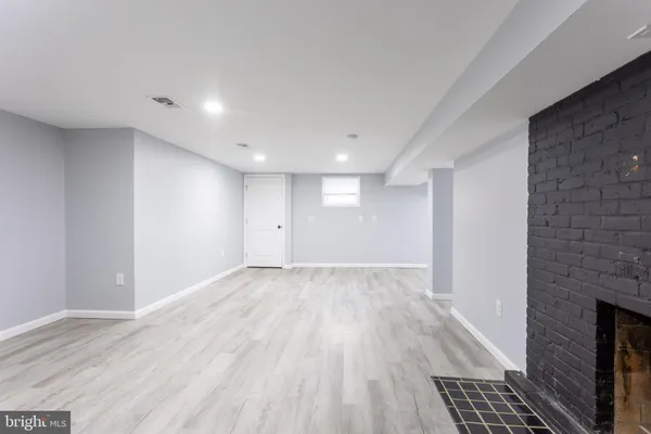 a view of an empty room with wooden floor and a fireplace