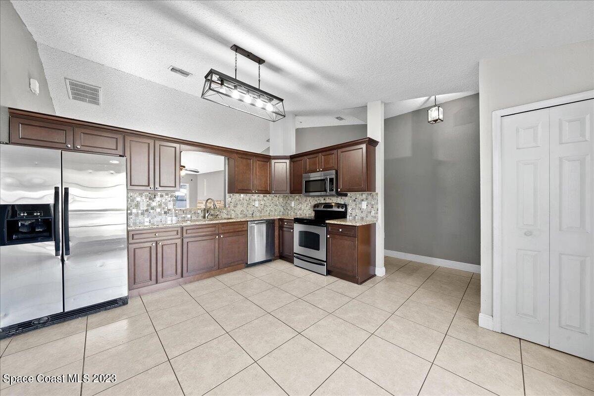 6949 Boston Road Cocoa, FL 32927 - Photo 6 of 33 a kitchen with stainless steel appliances granite countertop a refrigerator and a sink