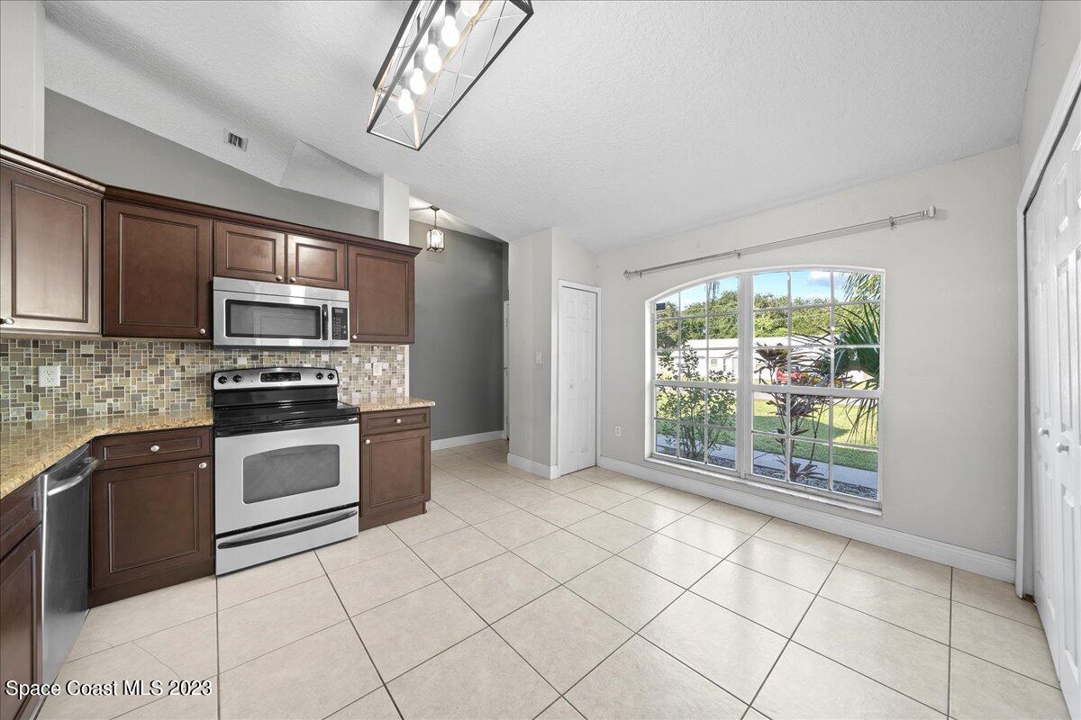 6949 Boston Road Cocoa, FL 32927 - Photo 7 of 33 a kitchen with stainless steel appliances granite countertop a stove a sink and a microwave