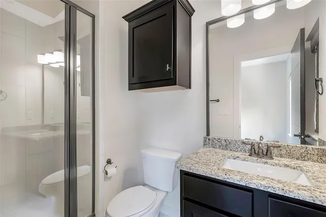 a bathroom with a granite countertop toilet sink and mirror